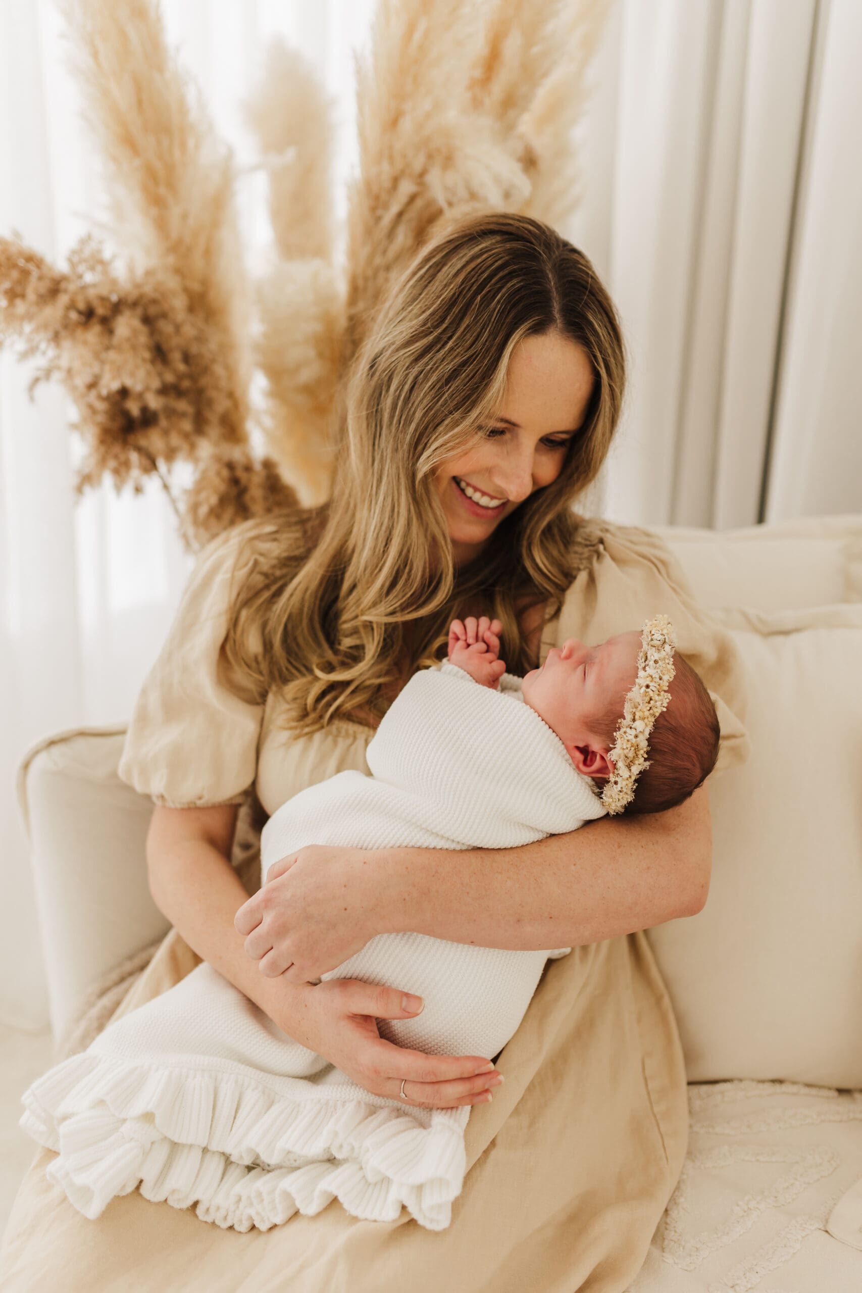 New mother resting with newborn baby in soft natural light during the fourth trimester